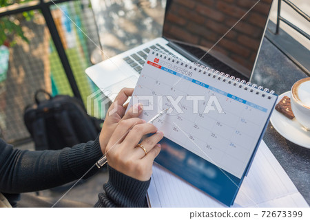 Businesswoman pointing on calendar by pen to remind about the meeting 72673399