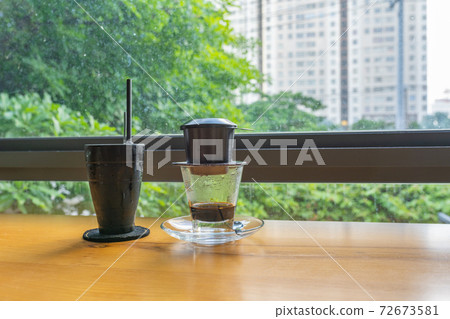 Vietnamese fin coffee with Saigon cityscape and green garden background Vietnamese fin coffee with Saigon cityscape and green garden background 72673581