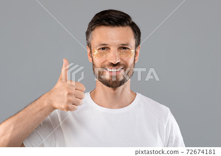 Middle-aged man with golden patches under eyes showing thumb up Middle-aged man with golden patches under eyes showing thumb up 72674181