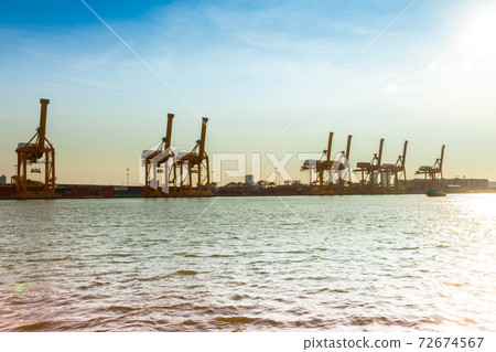 shipping crane of maritime transportation beside river  72674567