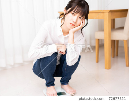 A young woman worried about riding a scale 72677831