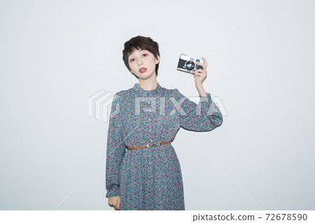 Young woman standing with a film camera Young woman standing with a film camera 72678590