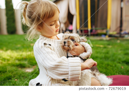 Kid embracing funny dog in the garden 72679019