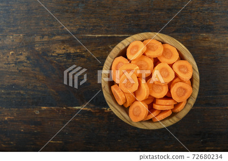 Sliced carrots in a bowl on a wooden background. Vegetable, ingredient and staple food. 72680234