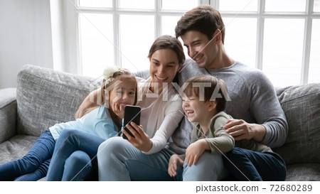 Close up happy parents with two kids using smartphone 72680289