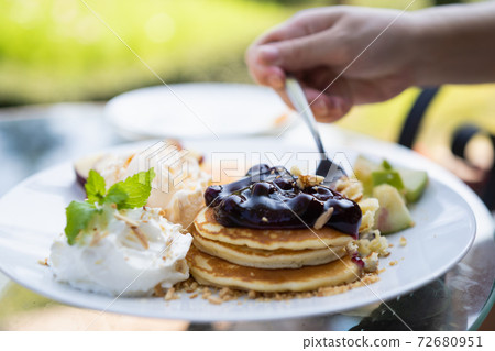 Hand of a woman eating pancakes on table in the cafe Hand of a woman eating pancakes on table in the cafe 72680951