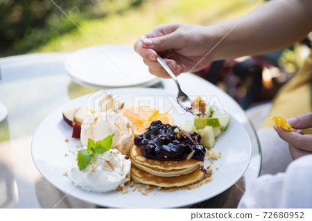 Hand of a woman eating pancakes on table in the cafe Hand of a woman eating pancakes on table in the cafe 72680952