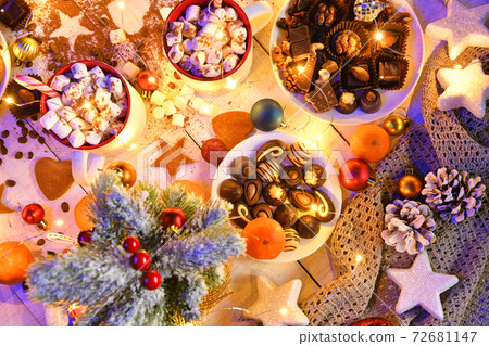 sweet food top view background for merry christmas or new year holiday decoration with night illumination - chocolate candies, tangerines, cookies, marshmallow and cocoa latte on white wood 72681147