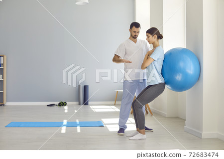 Professional osteopath controlling womans position during exercising with fitness ball Professional osteopath controlling womans position during exercising with fitness ball 72683474