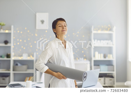Relaxed woman standing with fitness mat in hand after meditating or yoga practice Relaxed woman standing with fitness mat in hand after meditating or yoga practice 72683480