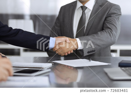 Unknown business people are shaking hands after contract signing in modern office, close-up. Handshake as successful negotiation ending Unknown business people are shaking hands after contract signing in modern office, close-up. Handshake as successful negotiation ending 72683481