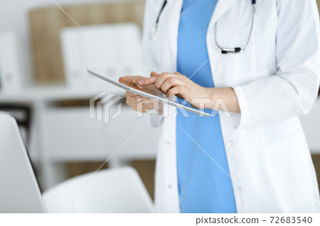 Unknown woman-doctor standing in clinic and using tablet pc, close-up. Data and best service in medicine and healthcare 72683540
