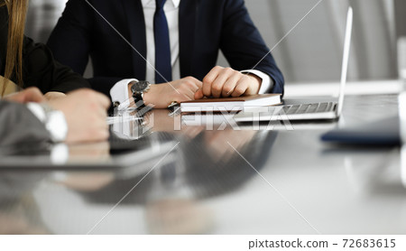 Unknown businessmen and woman sitting, working and discussing questions at meeting in modern office, close-up Unknown businessmen and woman sitting, working and discussing questions at meeting in modern office, close-up 72683615