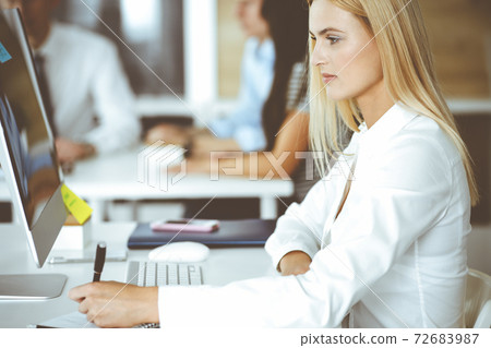 Business woman using computer at workplace in modern office. Secretary or female lawyer smiling and looks happy. Working for pleasure and success 72683987