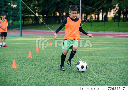 Soccer player kicking ball on field. Soccer players on training session. Teen footballer kicking ball on green grass. Soccer player kicking ball on field. Soccer players on training session. Teen footballer kicking ball on green grass. 72684547