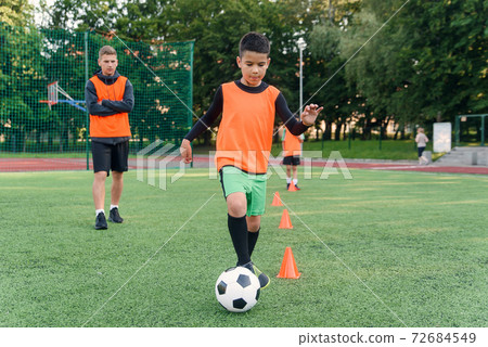 Soccer player kicking ball on field. Soccer players on training session. Teen footballer kicking ball on green grass. Soccer player kicking ball on field. Soccer players on training session. Teen footballer kicking ball on green grass. 72684549