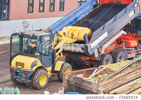 用輪胎挖掘機搬運裝載在自卸車上的瀝青的工作 72685019