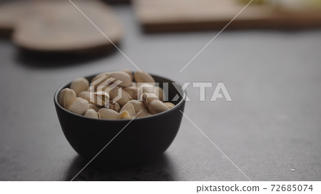 pistachios in black bowl on terrazzo surface 72685074