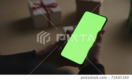 old female hands holding smartphone with green screen and celebrating holiday chatting with family old female hands holding smartphone with green screen and celebrating holiday chatting with family 72685160