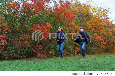 couple running in autumn city park, happy people together, beautiful nature with colorful leaves couple running in autumn city park, happy people together, beautiful nature with colorful leaves 72685602