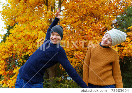 teen girl and boy in autumn city park, posing and playing on a background of yellow maple leaves, beautiful nature teen girl and boy in autumn city park, posing and playing on a background of yellow maple leaves, beautiful nature 72685604