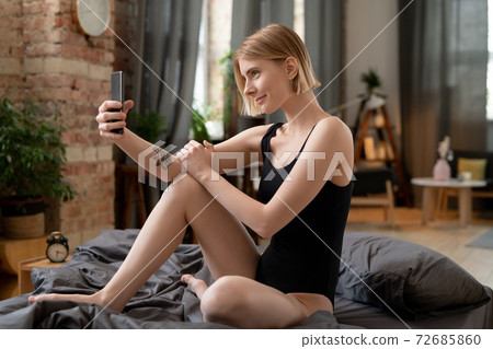 Happy young blond woman in black leotard making selfie or recording new video Happy young blond woman in black leotard making selfie or recording new video 72685860