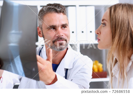 Mature male doctor hold in arm and look at xray photography 72686558