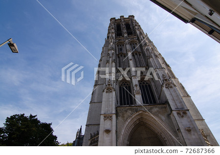 Mechelen, Belgium, August 2019. The imposing cathedral features a 97-meter bell tower in Gothic style. Beautiful summer day with blue sky. Mechelen, Belgium, August 2019. The imposing cathedral features a 97-meter bell tower in Gothic style. Beautiful summer day with blue sky. 72687366