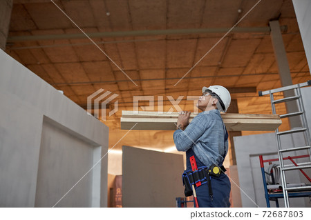 Female Worker Carrying Wood at Construction Site 72687803