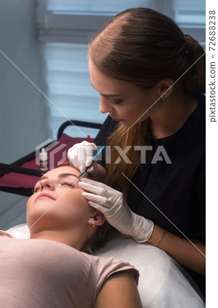 Beautician plucking eyebrows. Eyebrow care in a beauty salon. Beautician plucking eyebrows. Eyebrow care in a beauty salon. 72688238