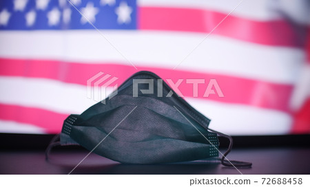 Disposable mask against blurred flag of the USA. American COVID-19 outbreak concept 72688458