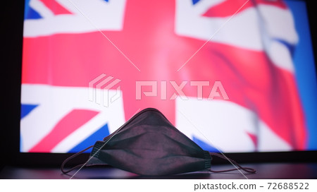 Disposable face mask against blurred flag of the UK. British COVID-19 outbreak concept 72688522