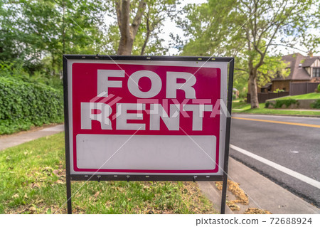 Close up of a real estate For Rent sign with road trees and sky background 72688924