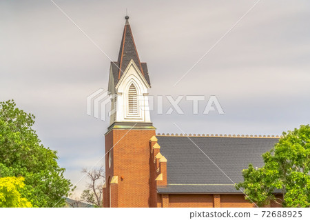 Side view of church exterior with focus on steeple and roof against cloudy sky 72688925