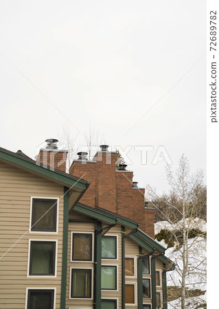 Townhomes with white exterior wall and red brick chimneys viewed in winter 72689782