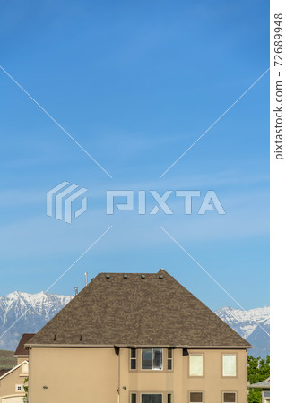 House exterior with blue sky and snow capped mountain background on a sunny day 72689948