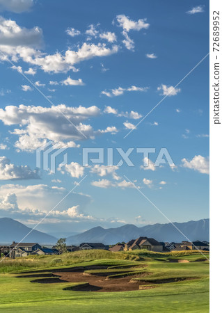 Scenic view of a golf course and residential area under blue sky on a sunny day Scenic view of a golf course and residential area under blue sky on a sunny day 72689952