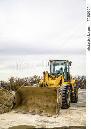 Focus on a yellow bulldozer with dirty bucket and wheels at a construction site 72689994