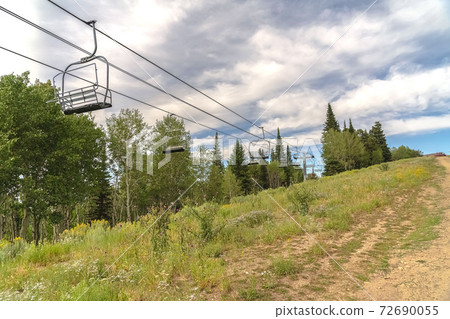 Chairlifts in Park City with a scenic aerial view of greenery during off season 72690055
