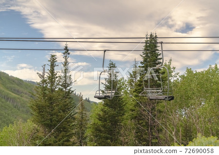Chairlifts and green trees against cloudy blue sky in Park City Utah in summer Chairlifts and green trees against cloudy blue sky in Park City Utah in summer 72690058