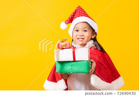 Kid dressed in red Santa Claus hat hold gift box on hands Kid dressed in red Santa Claus hat hold gift box on hands 72690430