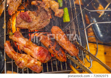Closeup photo of grilling barbecue meat on flaming charcoal stove Closeup photo of grilling barbecue meat on flaming charcoal stove 72692073