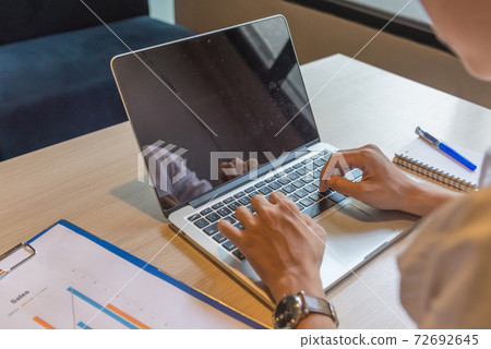Man typing laptop next to notebook and document at workplace 72692645
