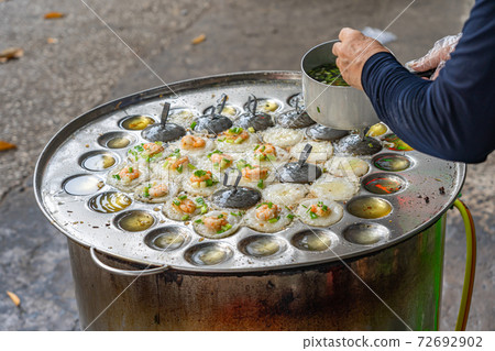 Woman making Banh Khot- Vietnamese tiny shrimp pancake on skillet 72692902