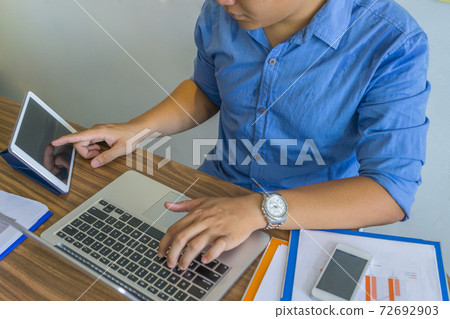 Young man working on laptop and tablet Young man working on laptop and tablet 72692903