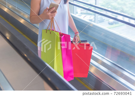 Woman holding shopping bags and smartphone Woman holding shopping bags and smartphone 72693041