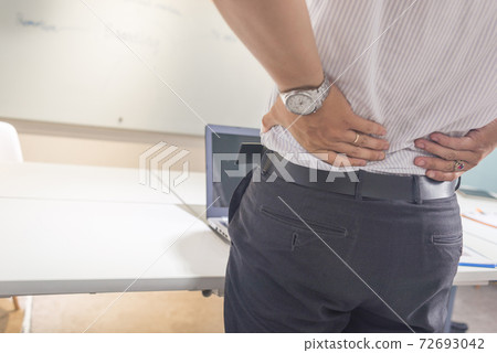 Businessman suffering from backache in office 72693042