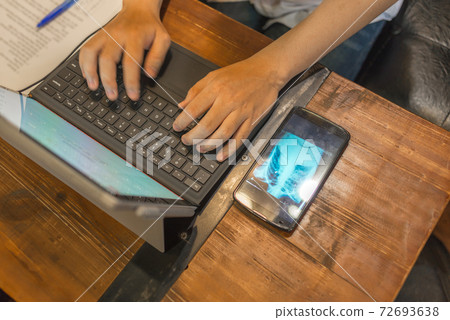 Doctor typing laptop and showing chest x-ray result on cellphone Doctor typing laptop and showing chest x-ray result on cellphone 72693638