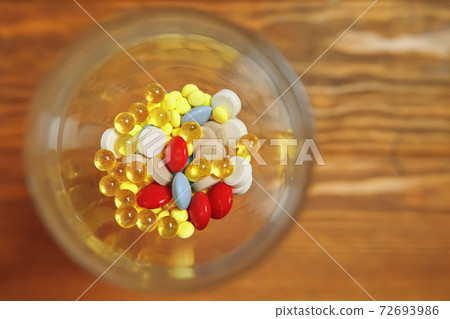Top view of glass with vitamins and pills inside. Top view of glass with vitamins and pills inside. 72693986