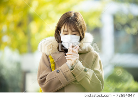 Woman in coat and mask 72694047